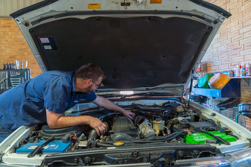 4WD logbook servicing — mechanic working on engine